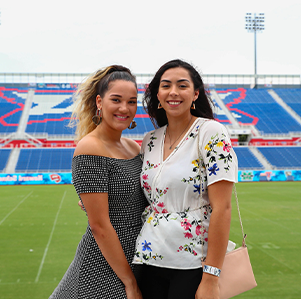Two female alumni standingon the FAU football field